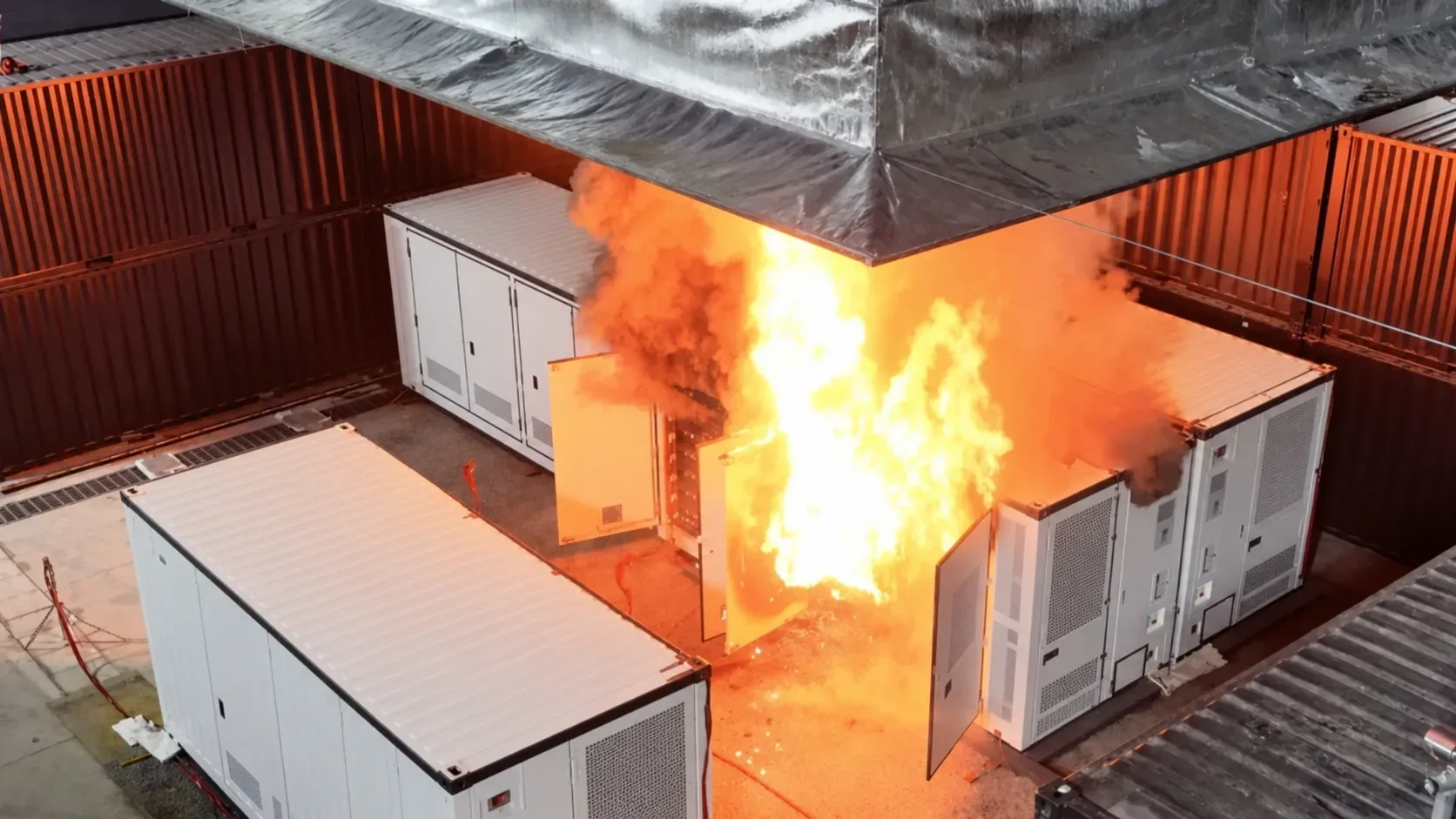 Bearbeitete Illustration eines großskaligen Brandversuchs mit neutralisierten Batteriespeicher-Gehäusen